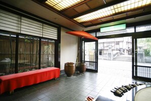 A traditional Japanese room with tatami flooring, a red bench, large ceramic vases, and a sliding door leading to an outdoor area. - Kinosaki Onsen Kawaguchiya Honkan (Toyooka)