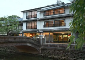 Un edificio tradicional japonés con varias ventanas y un puente de piedra en primer plano.