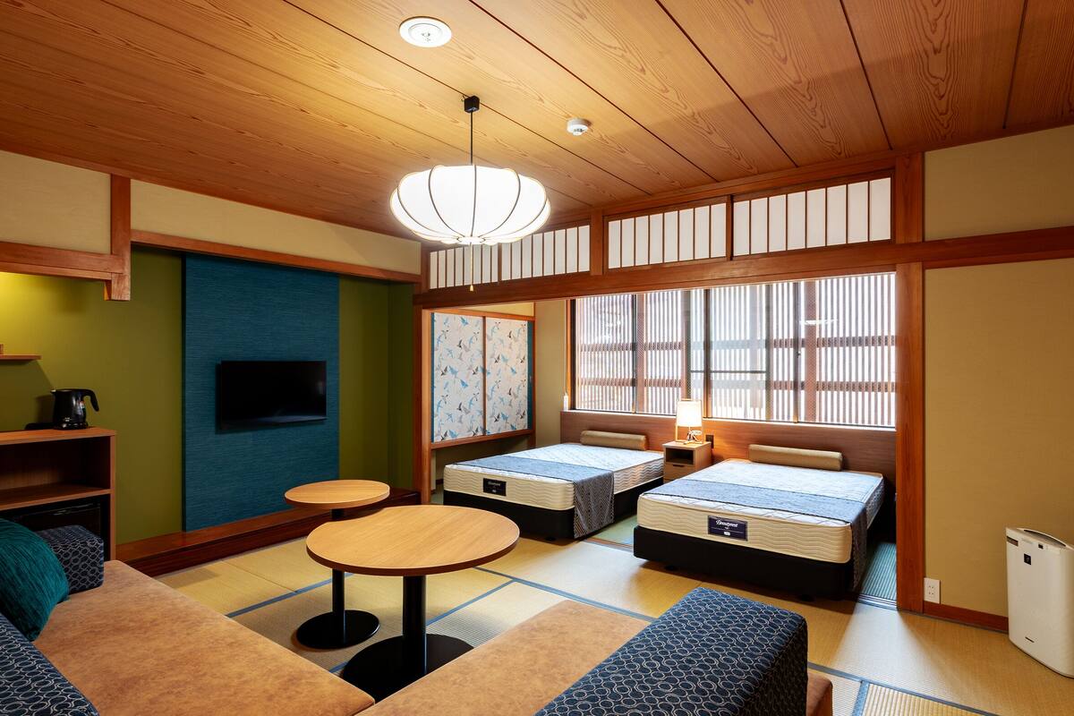 A traditional Japanese-style room with tatami flooring, low tables, and futon beds.
