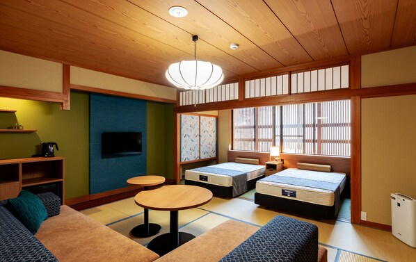 A traditional Japanese-style room with tatami flooring, low tables, and futon beds. - Kinosaki Onsen Kawaguchiya Honkan (Toyooka)