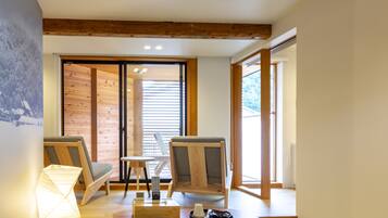 Una habitación con techo de madera, puerta corredera y vistas al exterior. Hay dos sillas, una mesa y una lámpara.