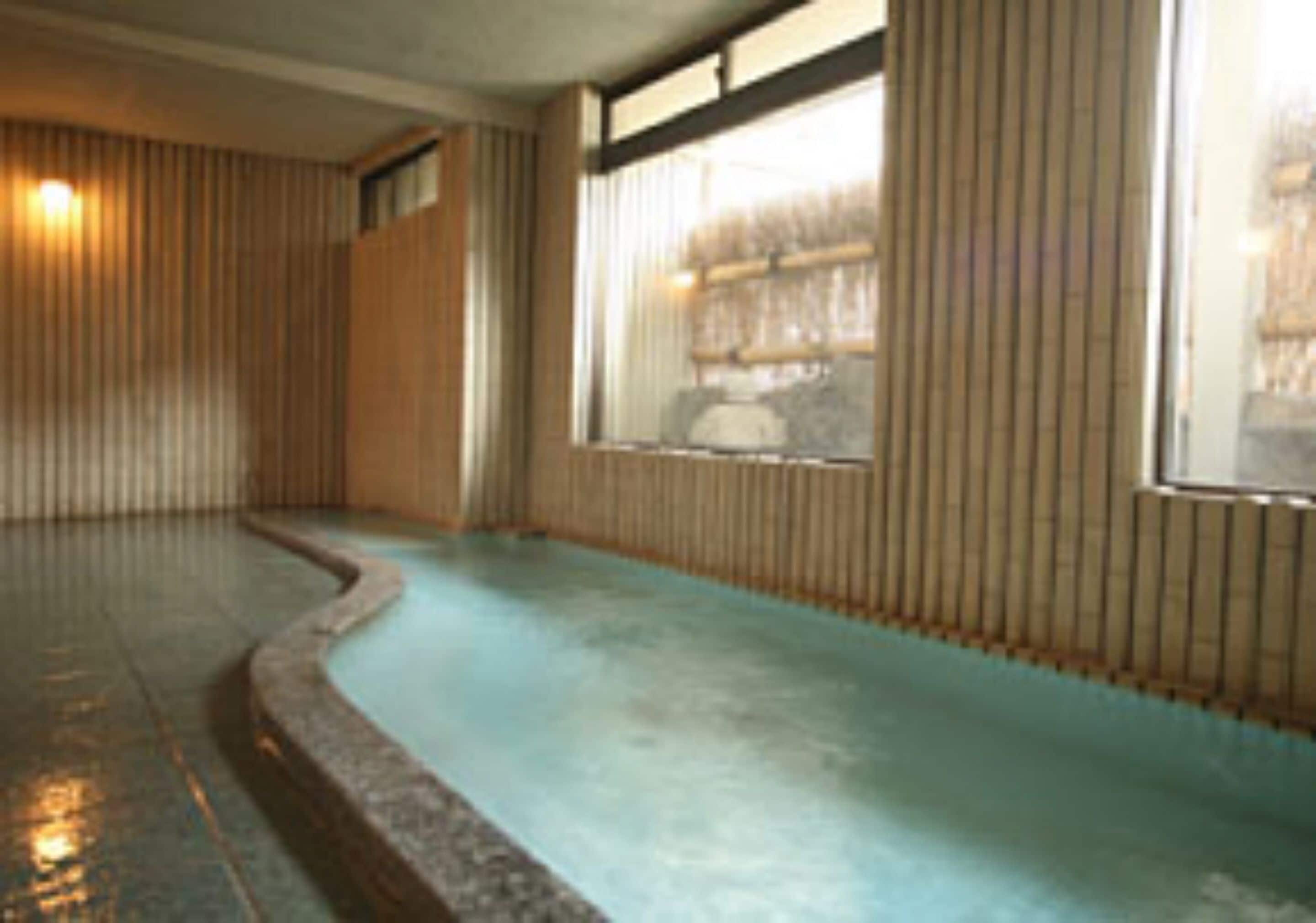 A room with a curved blue floor, wooden panel walls, and a window with vertical blinds.