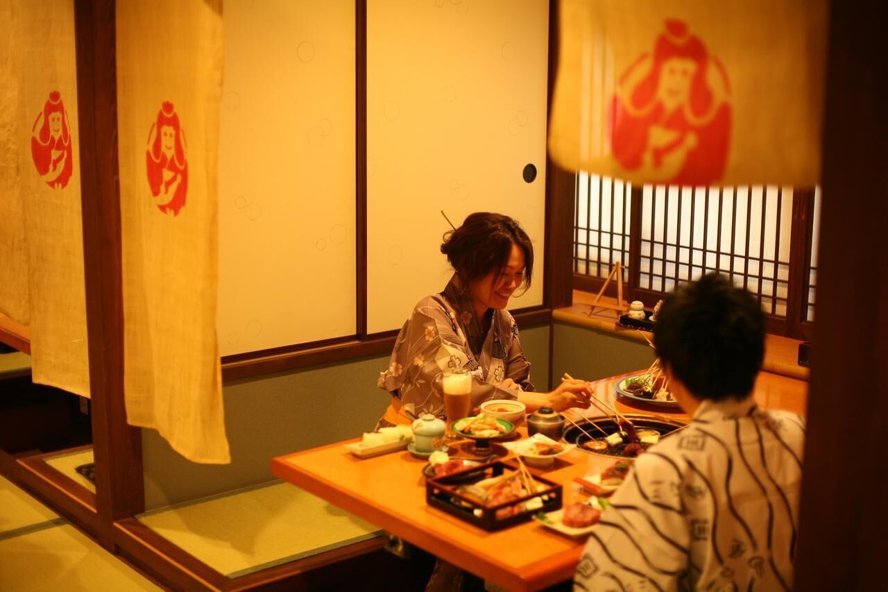 Ein traditioneller japanischer Speisesaal mit Tanzbodenmatten, niedrigen Tischen und Schiebetüren.