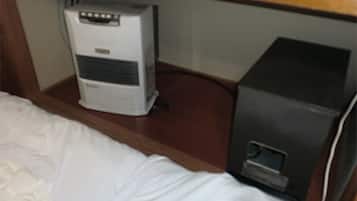 Una cama con edredón blanco y un calentador pequeño blanco debajo.