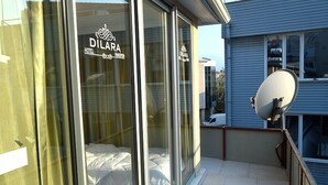 A hotel room with large glass windows, a bed, and a satellite dish on the balcony. - Dilara Hotel (Antalya)