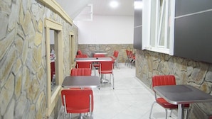 A dining area with stone walls, red chairs, and tables. - Dilara Hotel (Antalya)