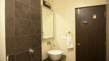 A bathroom with a white sink, dark brown tiles, a mirror, and a door with a lock.