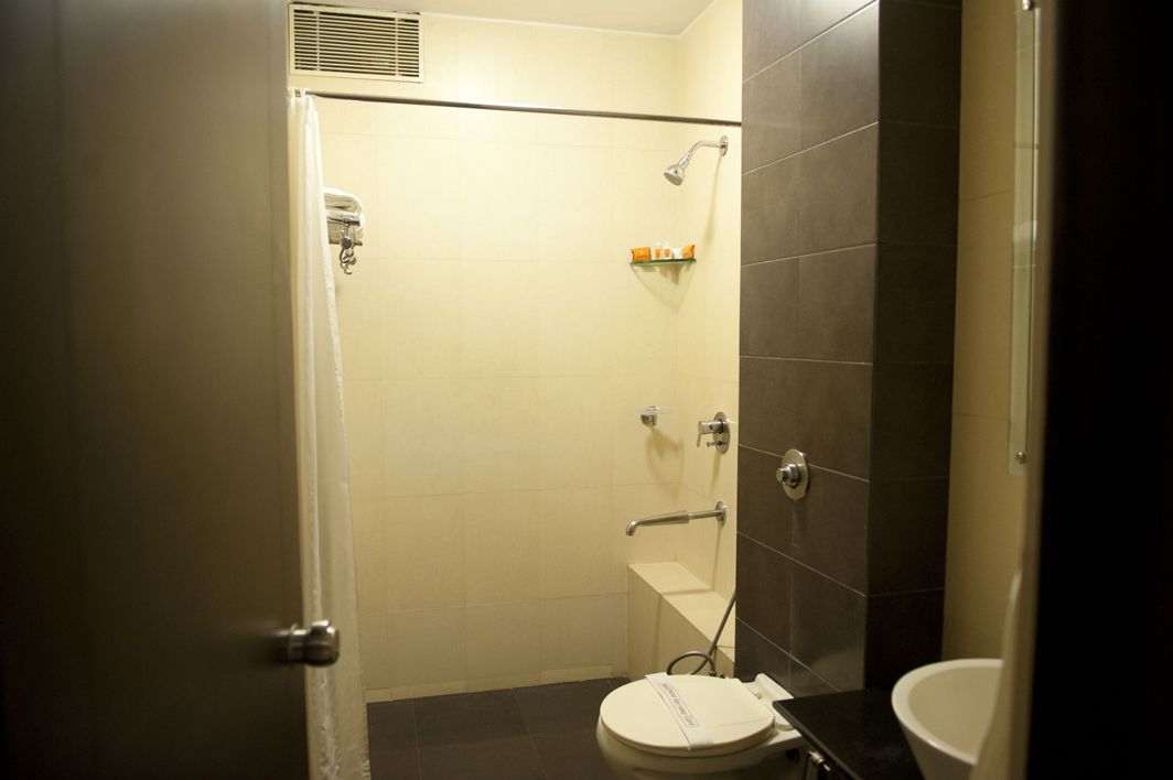 A small, enclosed bathroom with a toilet, a shower stall, and a sink.