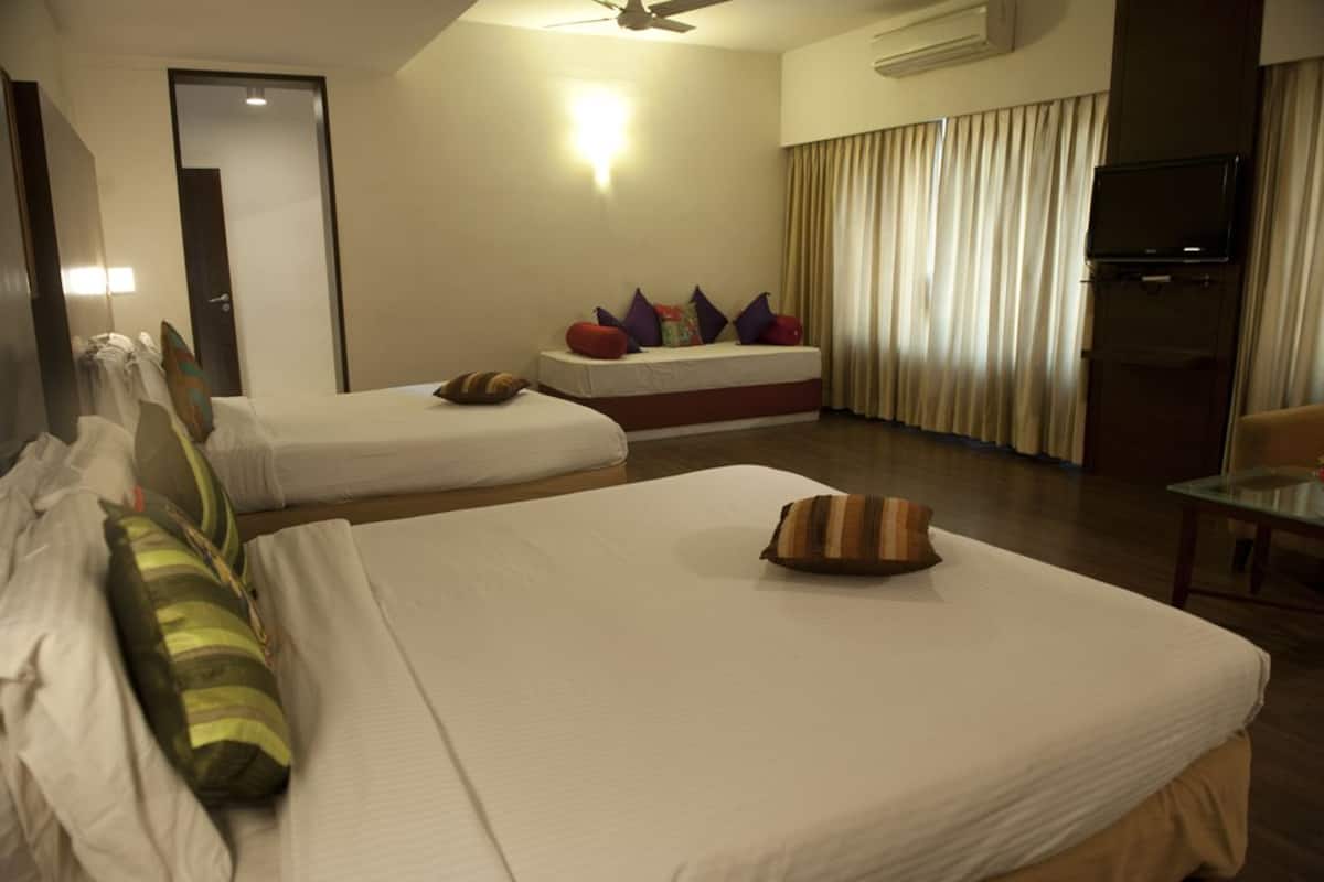 Habitación de hotel con dos camas, televisor y ventilador de techo.