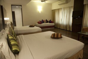 A hotel room with two beds, a television, and a ceiling fan. - Hotel Siddharta (Mysore)