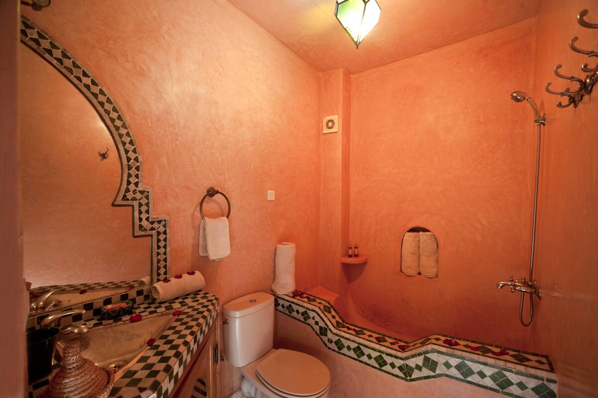 Un baño con piso a cuadros, inodoro, lavamanos y ducha.