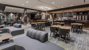 A modern hotel lobby with seating areas, a bar, and a reception desk.