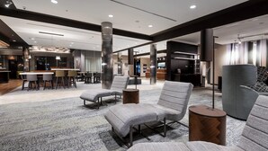 A modern hotel lobby with seating areas, a bar, and a reception desk.