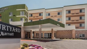 A Courtyard Marriott hotel entrance with a modern design, featuring a prominent sign, a covered parking area, and a brick facade.