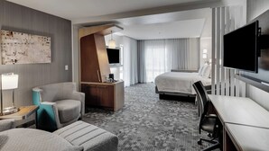 A modern hotel room with a large bed, a desk, a chair, a TV, and a painting on the wall.