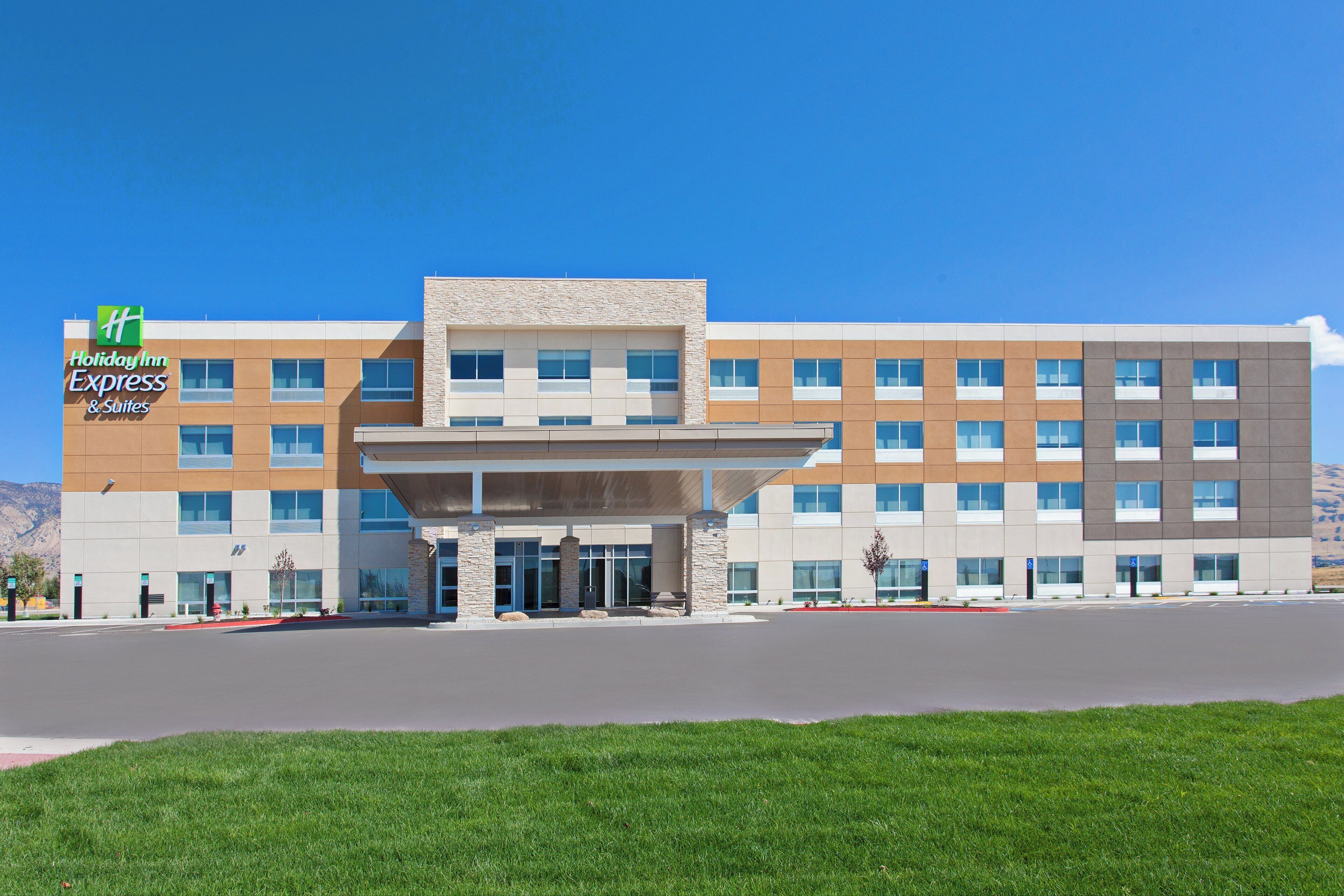 A Holiday Inn Express & Suites hotel with a modern design, featuring a flat roof, large windows, and a central entrance.