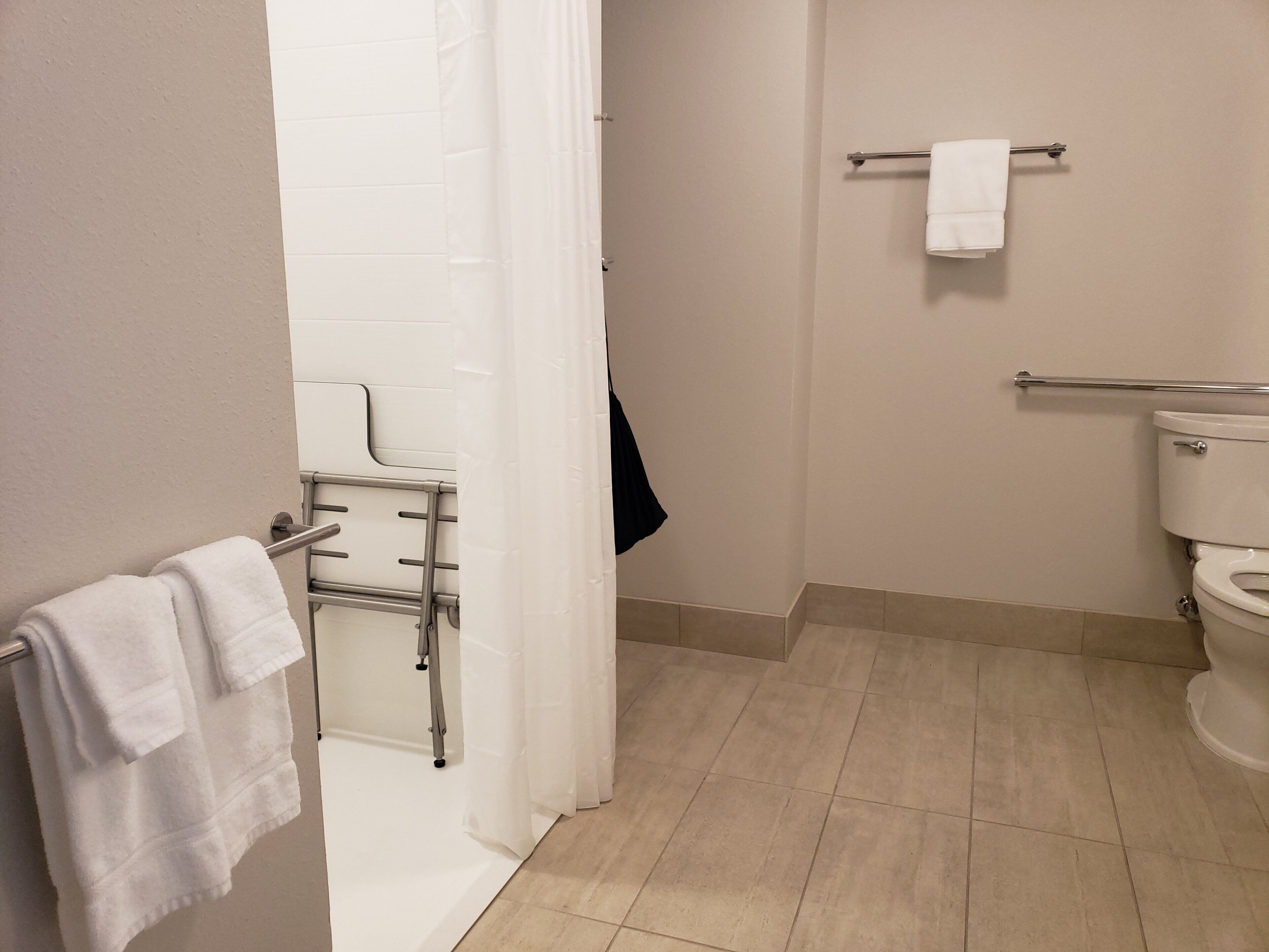 Un baño con ducha, inodoro y perchero para toallas.
