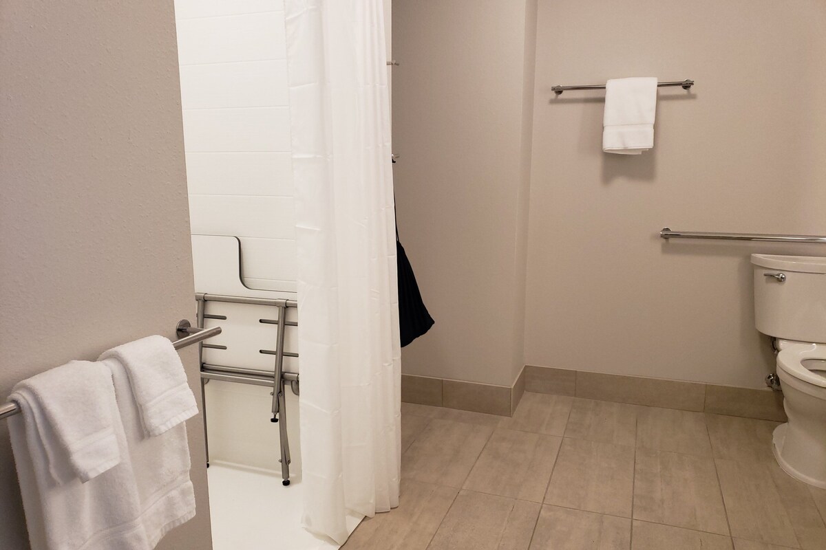 A bathroom with a shower, a toilet, and a towel rack.