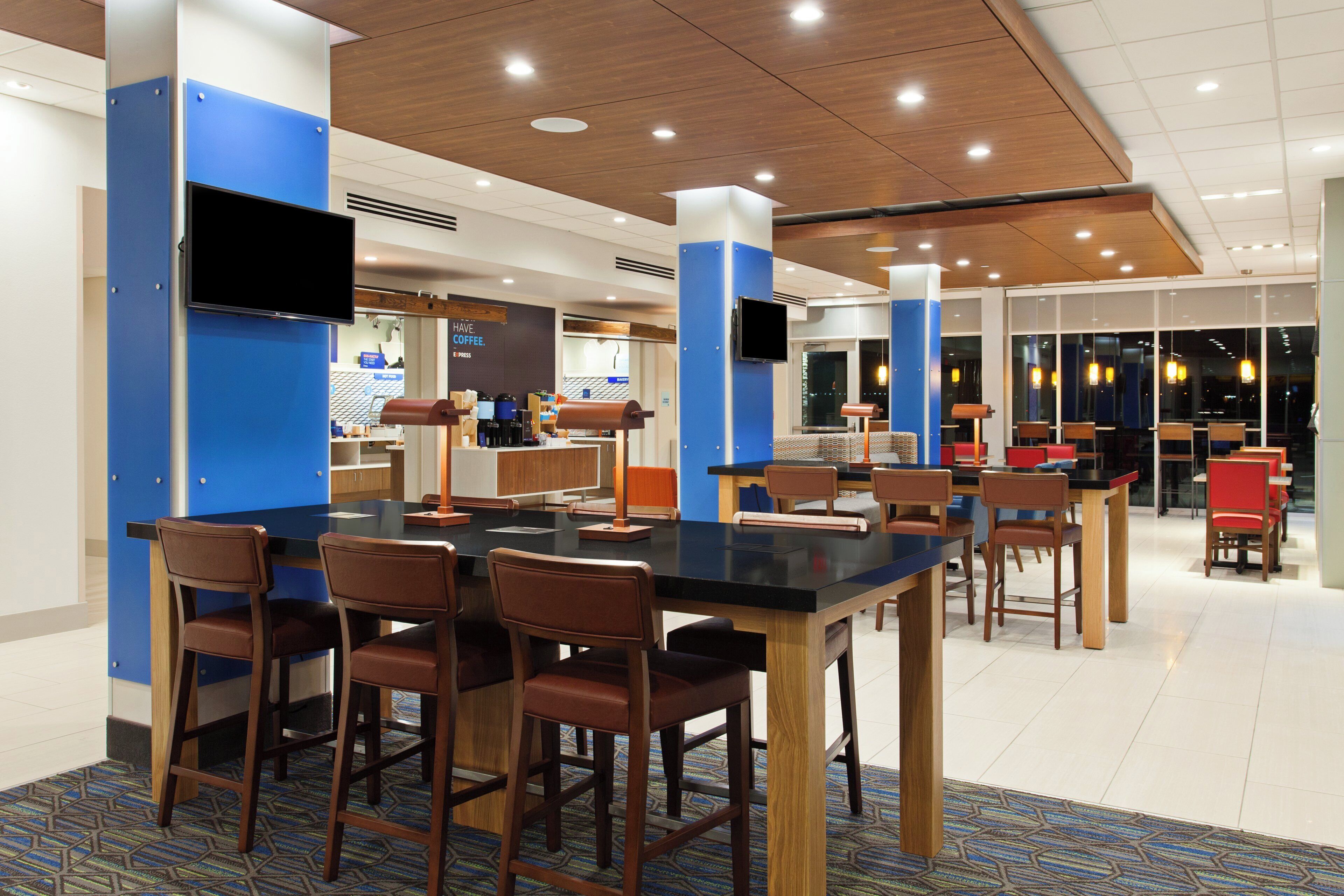 A modern dining area with a long table, multiple chairs, and a coffee station.