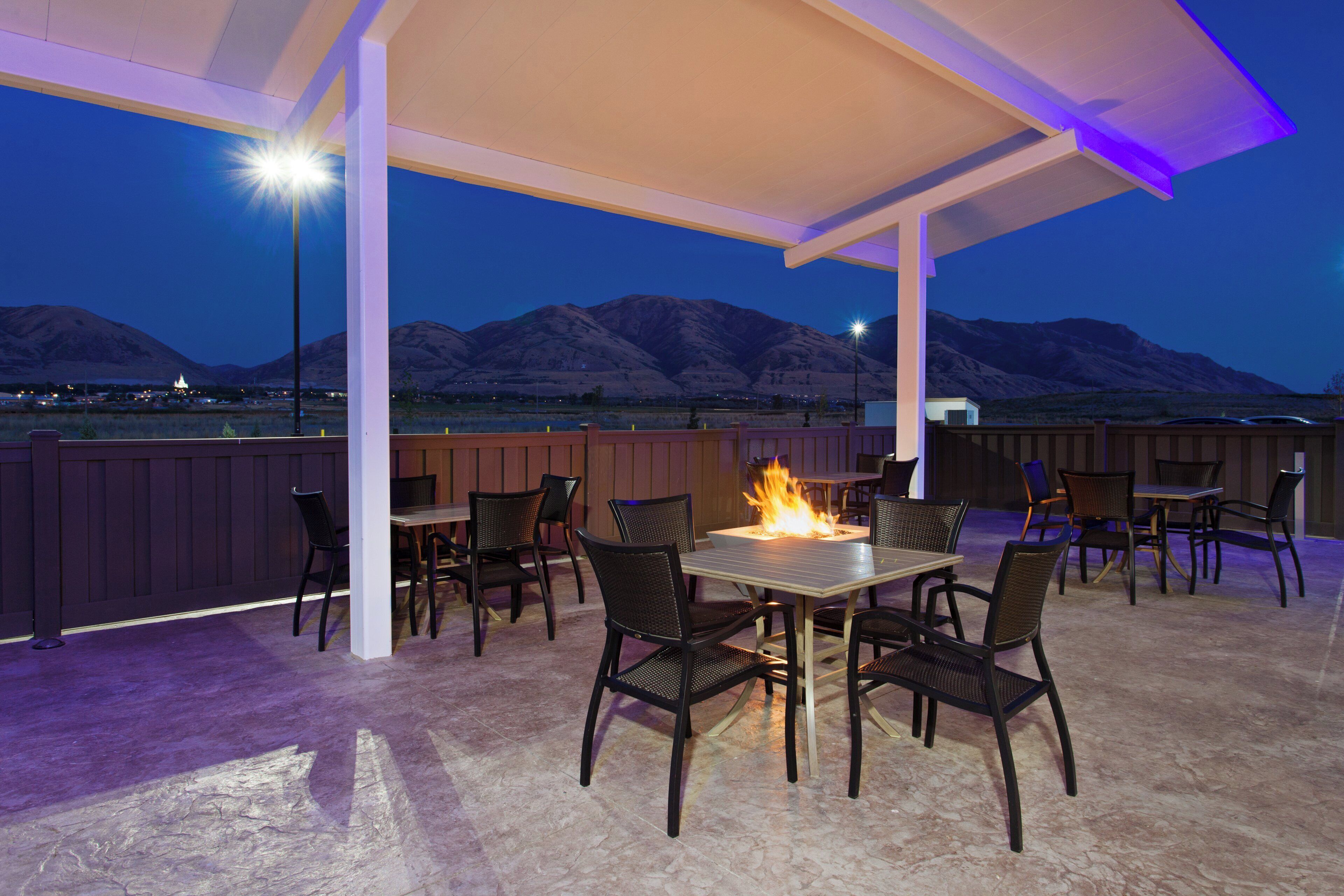 An outdoor patio with a fire feature, seating, and a view of mountains.