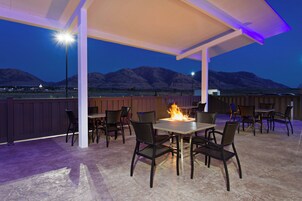 Un patio exterior con una chimenea, asientos y vistas a montañas.