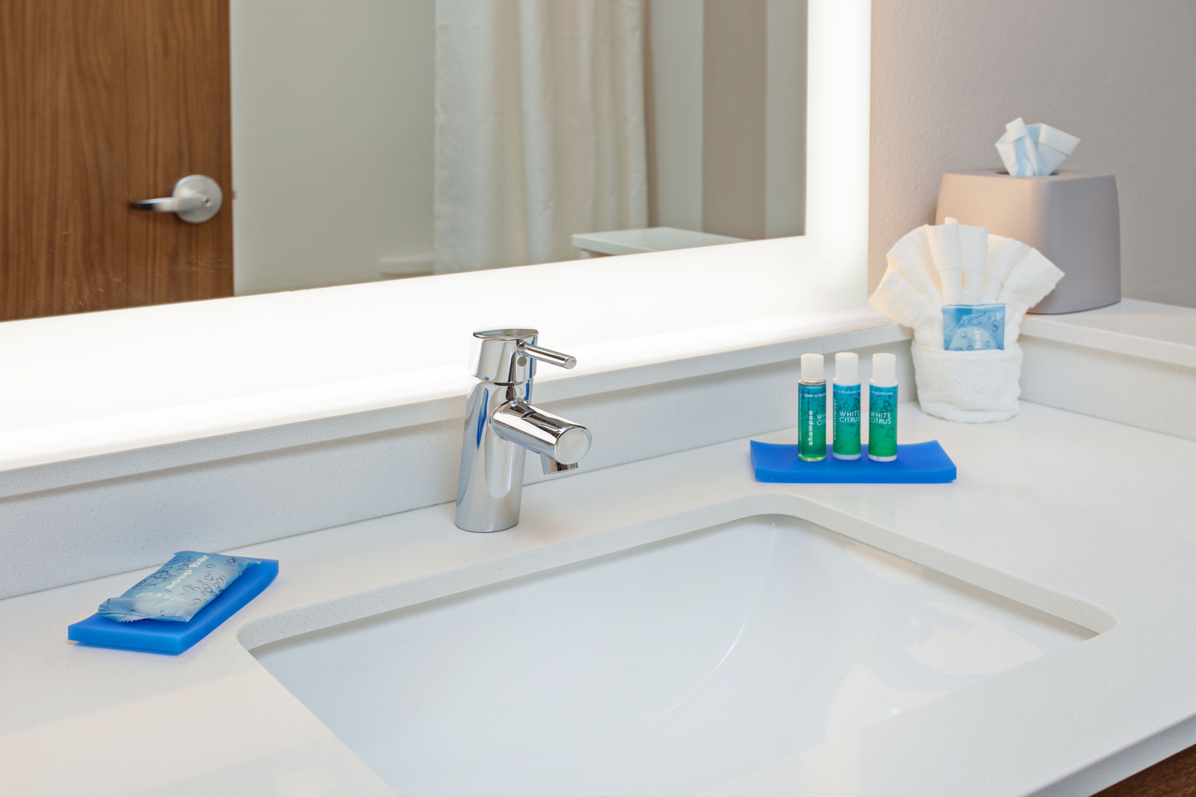 A bathroom with a white sink, a mirror, and a tissue box.
