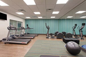 Gimnasio con cintas de correr, elípticas y una bicicleta estática.