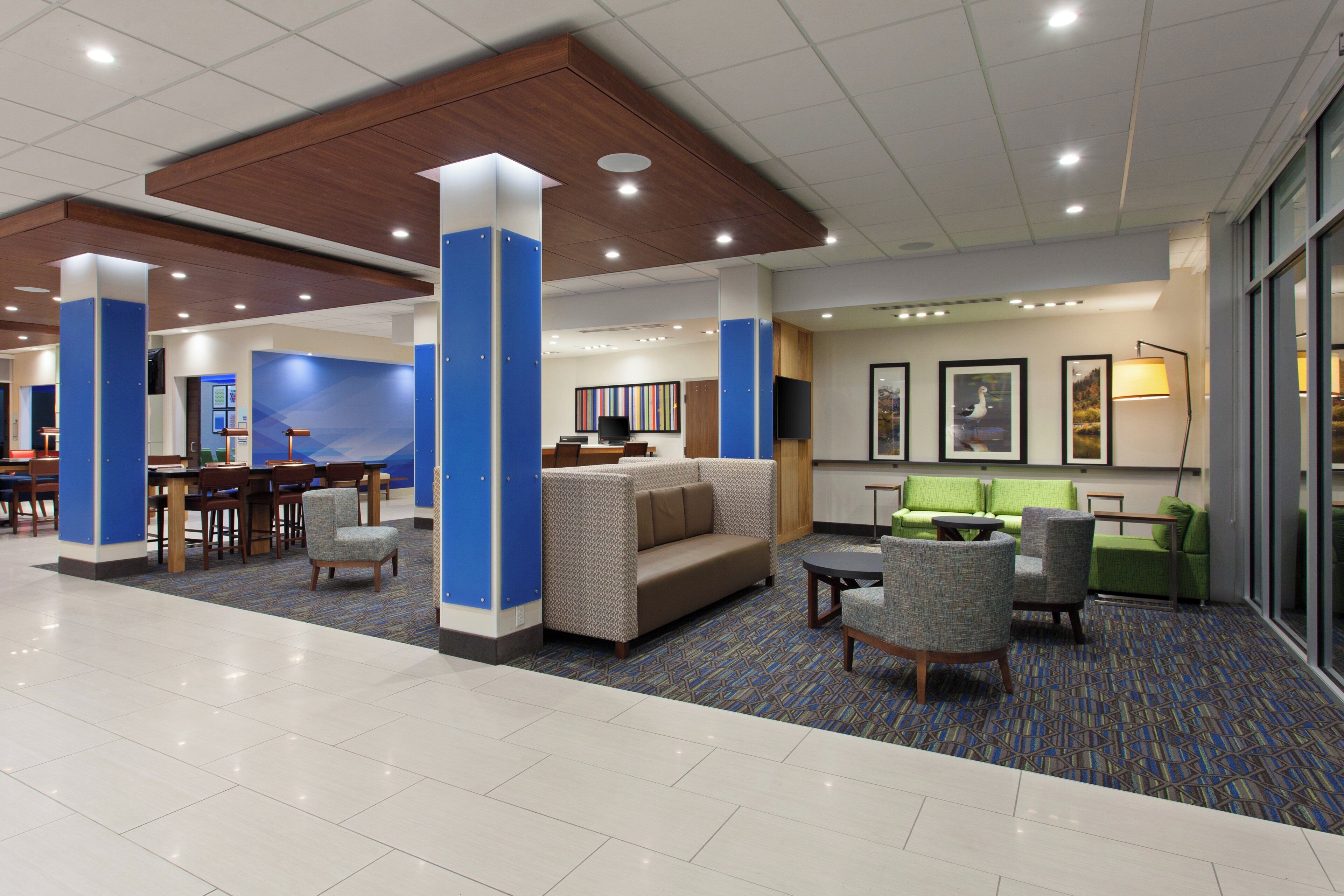 A hotel lobby with a seating area, a reception desk, and a television.