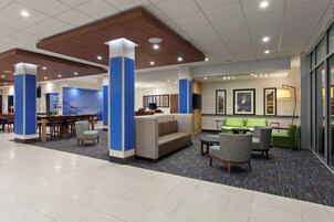 Un vestíbulo de hotel con una zona de estar, una recepción y un televisor.