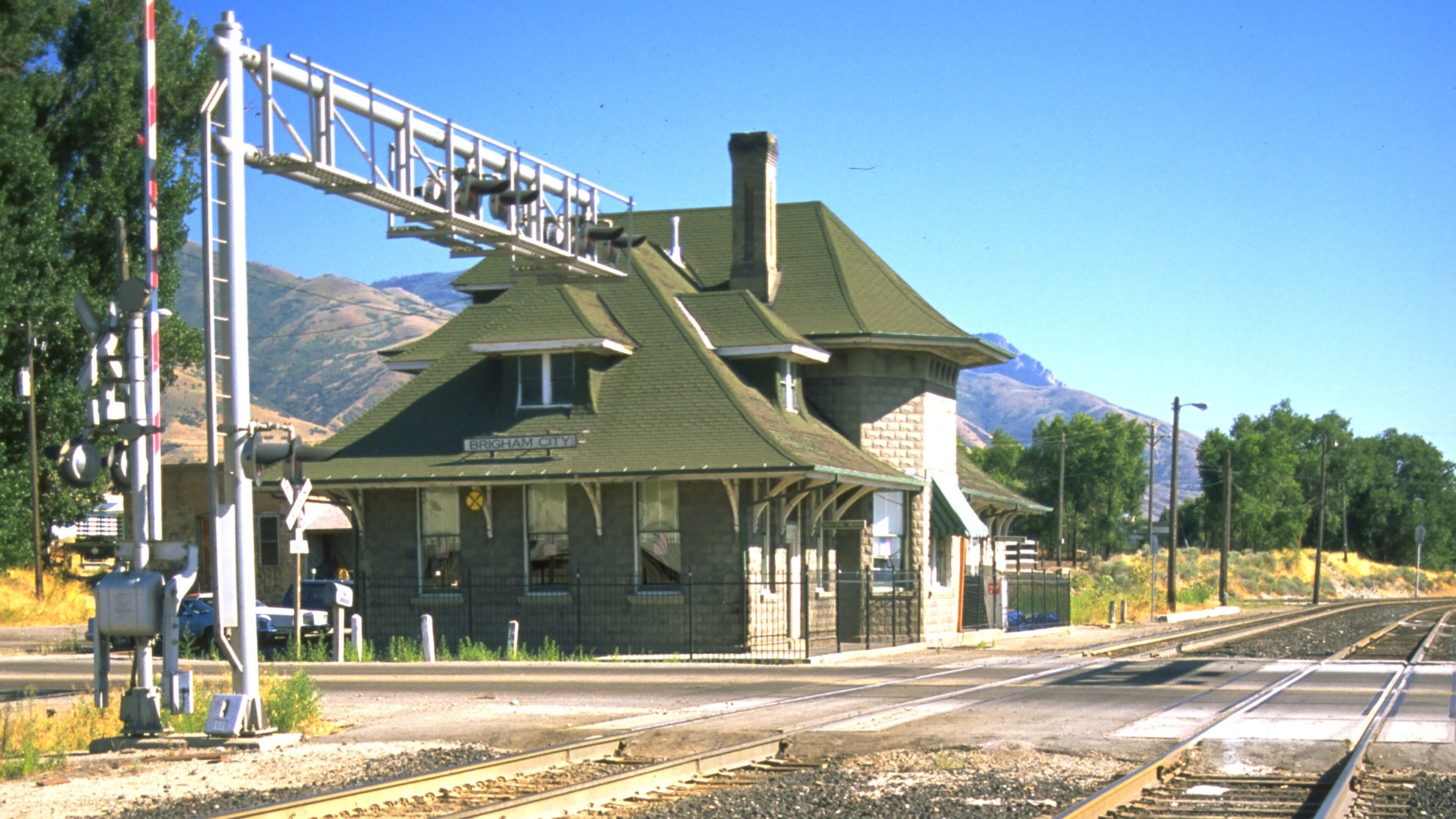 A train station with a brick building, a platform, and a railway track.