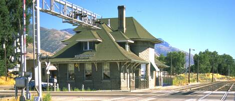 A train station with a brick building, a platform, and a railway track.