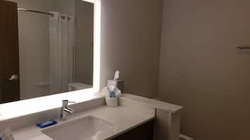 Un baño con un espejo grande, un lavabo, un perchero para toallas y un inodoro.