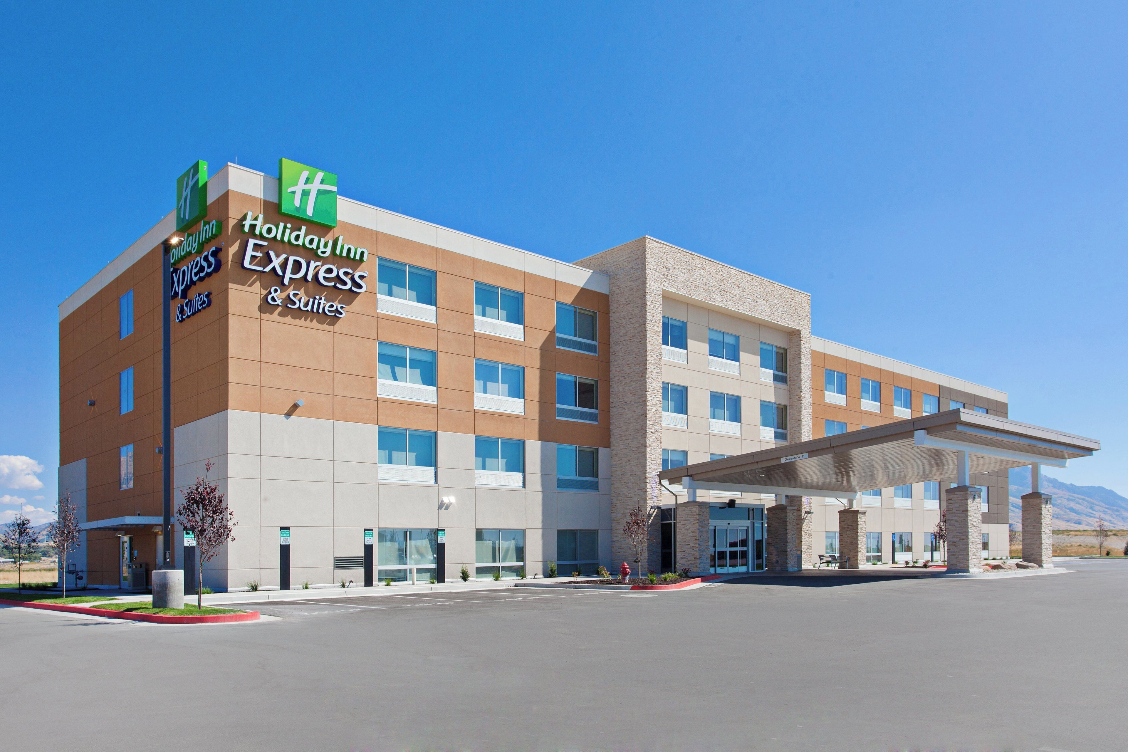 A Holiday Inn Express & Suites hotel with a modern design, featuring a flat roof and a covered entrance.
