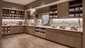 A modern kitchen with built-in shelves, a glass backsplash, and a variety of kitchenware. - Hyatt House Raleigh / RDU / Brier Creek (Raleigh)