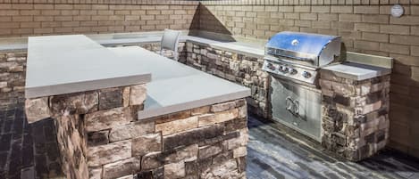 Cocina exterior con encimera de piedra y parrilla integrada.