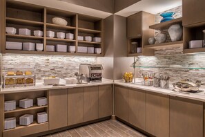 Een moderne keuken met inbouwplanken voor servies en bestek, een koffieapparaat en een glazen spatwand.