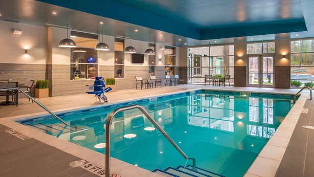 An indoor swimming pool with clear water, a no diving sign, and a seating area with chairs and tables. - Hyatt House Raleigh / RDU / Brier Creek (Raleigh)