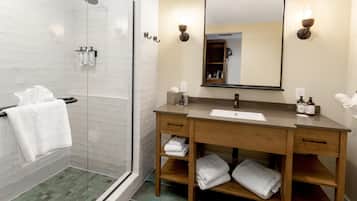 A modern bathroom with a glass shower, wooden vanity, and a large mirror.