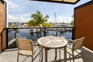 A balcony with a view of a marina, featuring a table and two chairs.