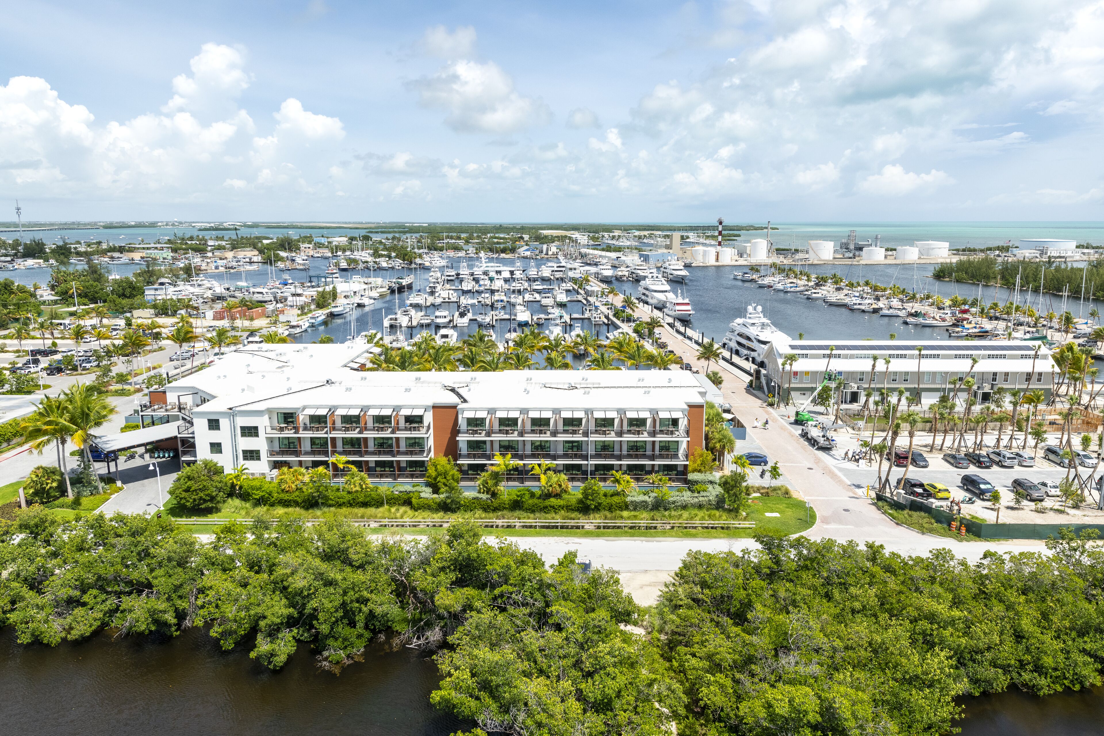 A marina with numerous boats, a modern building with large windows, and a view of the ocean.