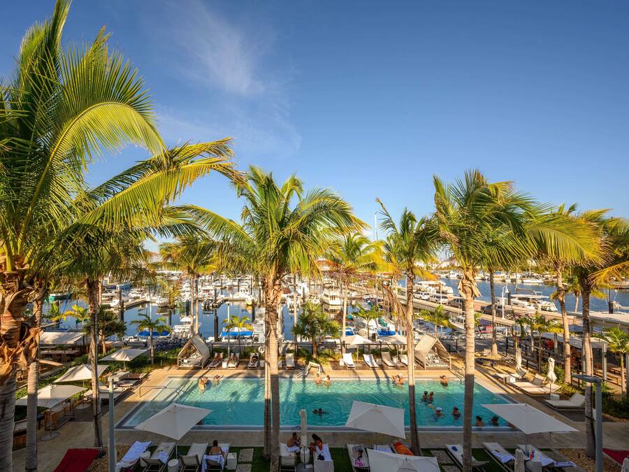 Un resort con varias piscinas rodeadas de palmeras y zonas de descanso.