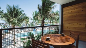 A balcony with a wooden table and chairs, overlooking a swimming pool and palm trees. - The Perry Hotel & Marina Key West (Key West)