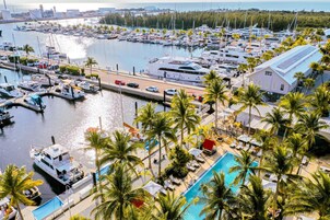 Un puerto deportivo con barcos amarrados, una piscina y palmeras.