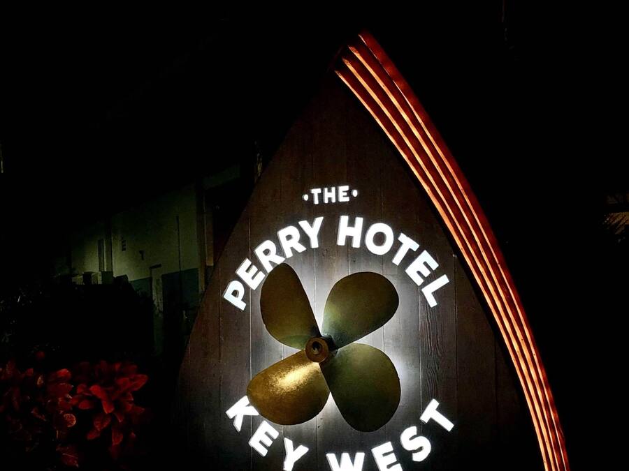 A sign for The Perry Hotel Key West, featuring a propeller design and illuminated text.