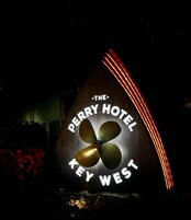 A sign for The Perry Hotel Key West, featuring a propeller design and illuminated text.