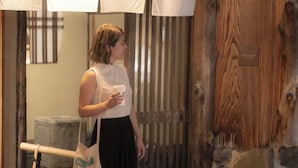 A person holding a Starbucks cup and a bag with "SMALL ST" on it, standing near a wooden wall with a plaque.