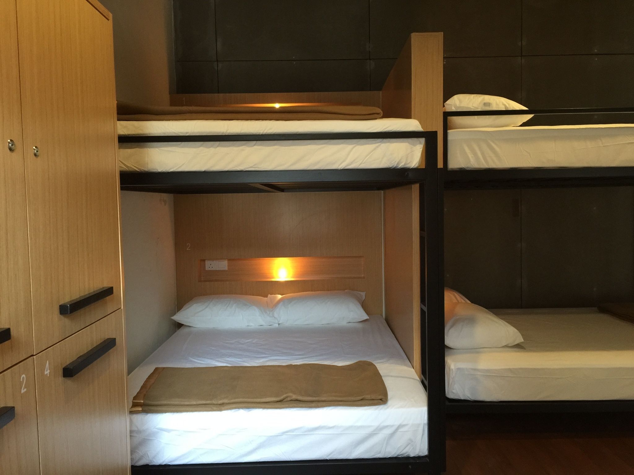 A bunk bed room with wooden cabinets and a single bed with a brown blanket.