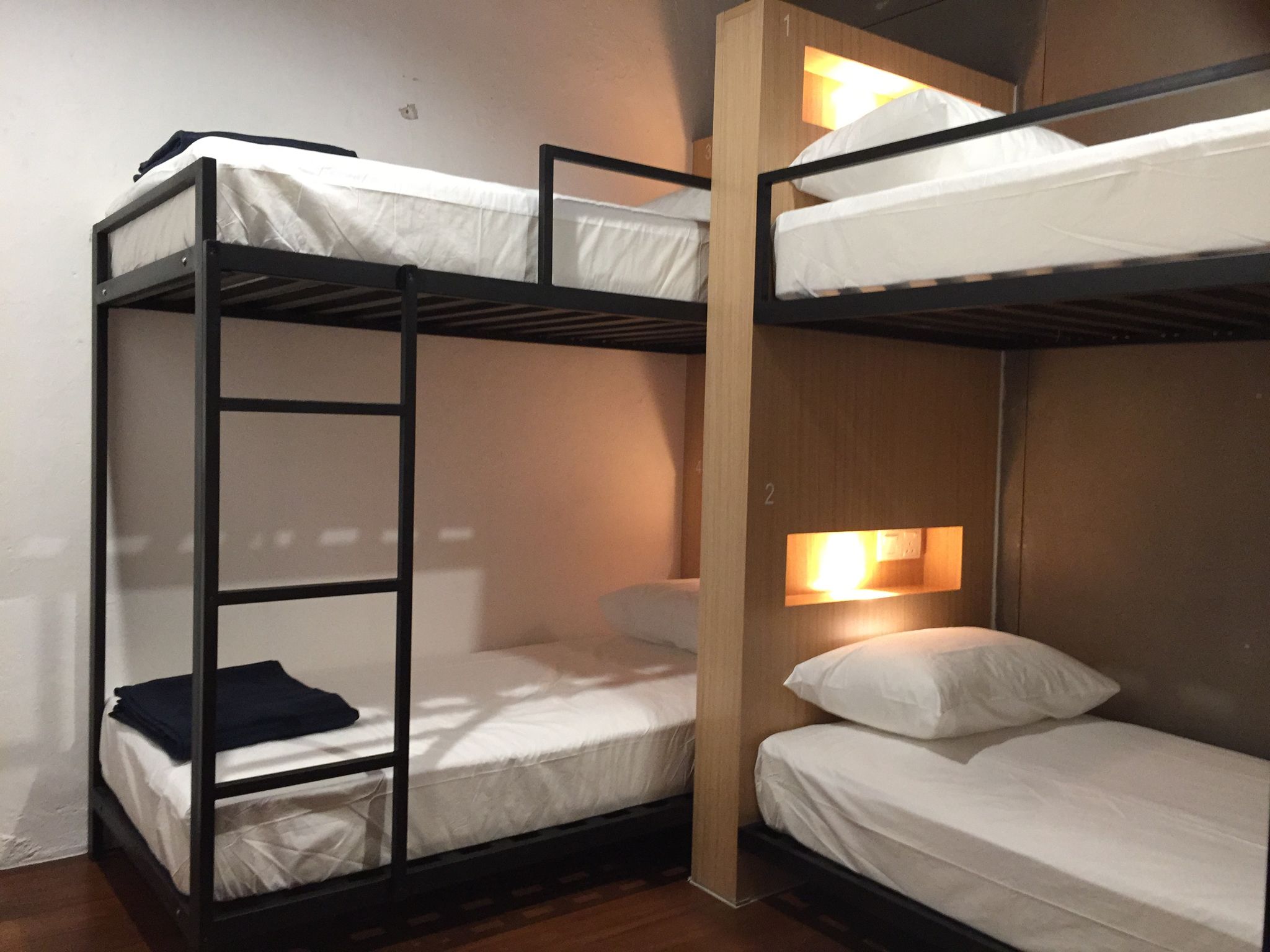 A bunk bed room with a wooden ladder, a night light, and a wooden wall.