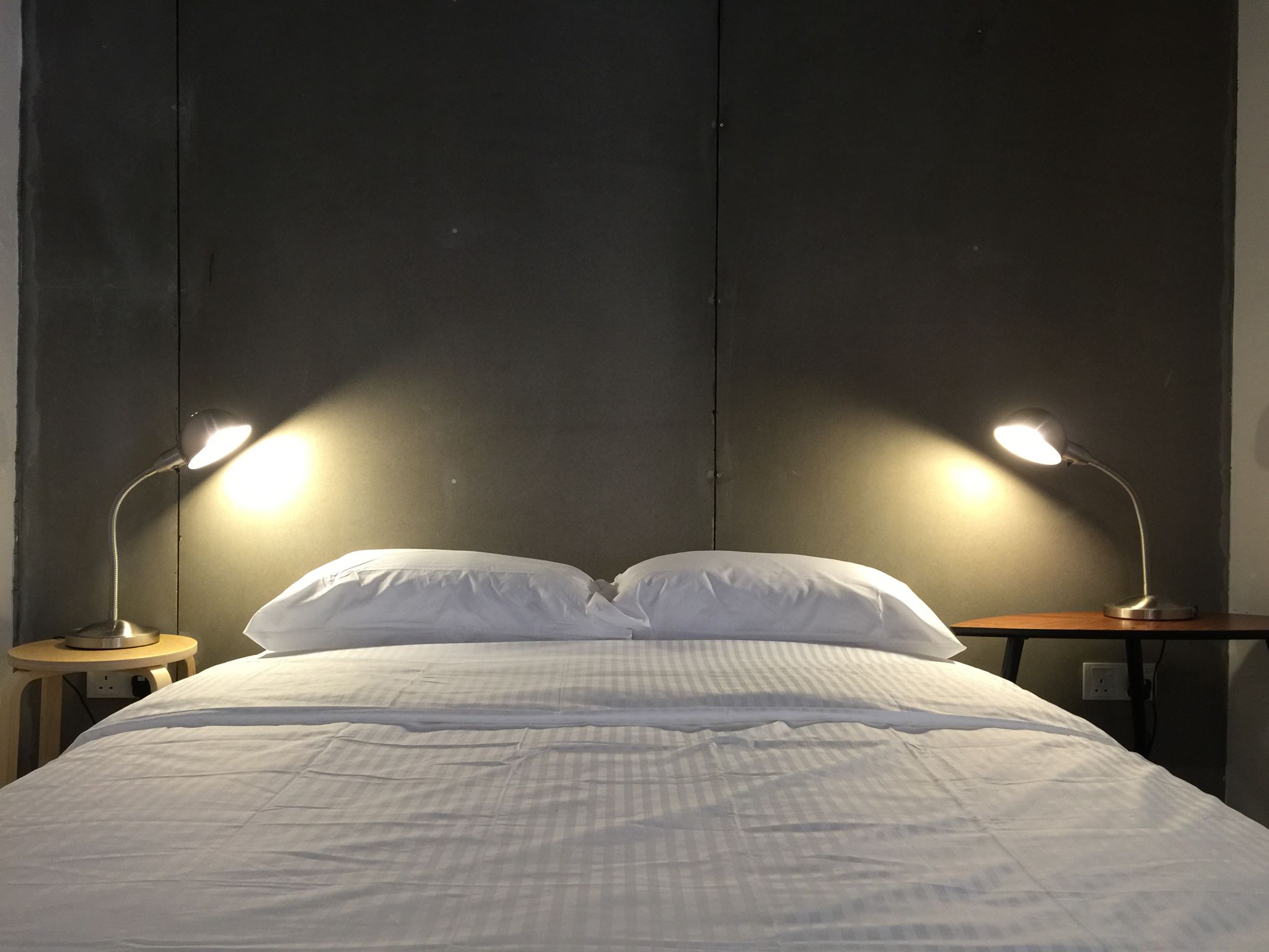 A neatly made bed with white bedding and two bedside lamps on wooden nightstands.