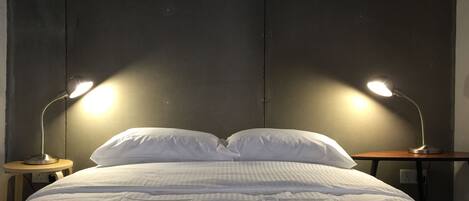 A neatly made bed with white bedding and two bedside lamps on wooden nightstands.